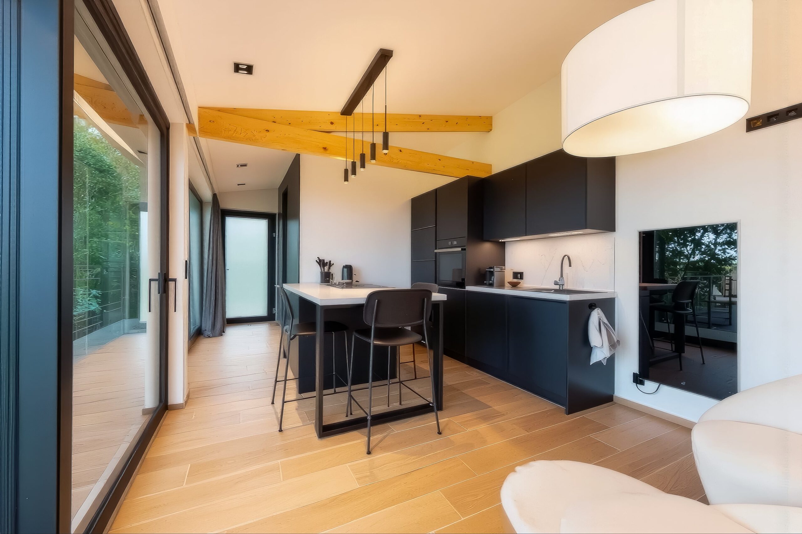 Cuisine moderne noire K-Lita avec îlot central dans un gîte lumineux à Gesves, mariant façades mates, parquet chêne et poutres apparentes.